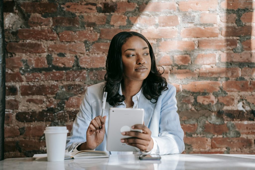 Businesswoman with a tablet sits thoughtfully in a café, capturing modern work vibes.